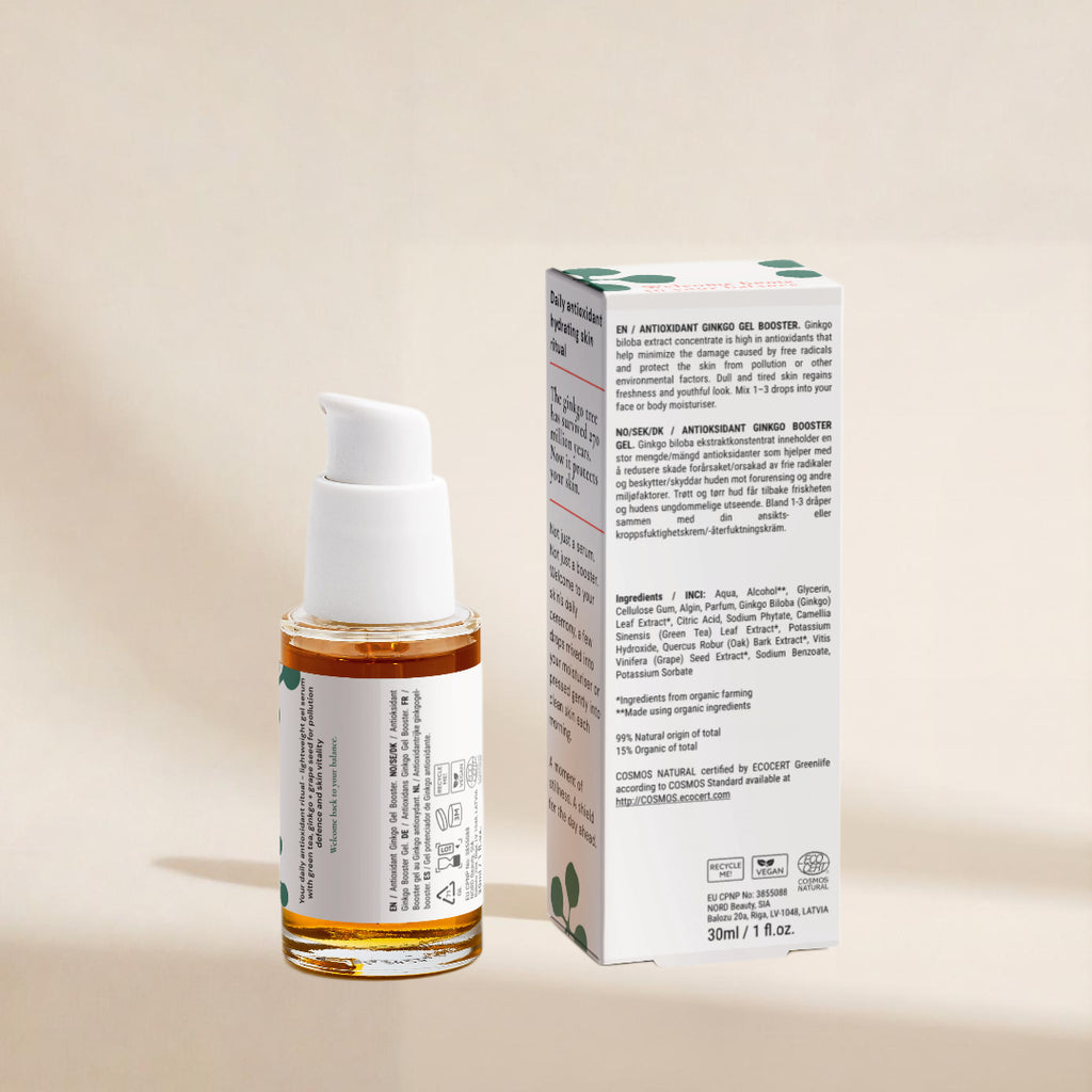 A bottle of serum alongside its product box, both featuring white labels and caps, with the serum inside the clear bottle appearing amber-brown. The packaging has green leaf accents.