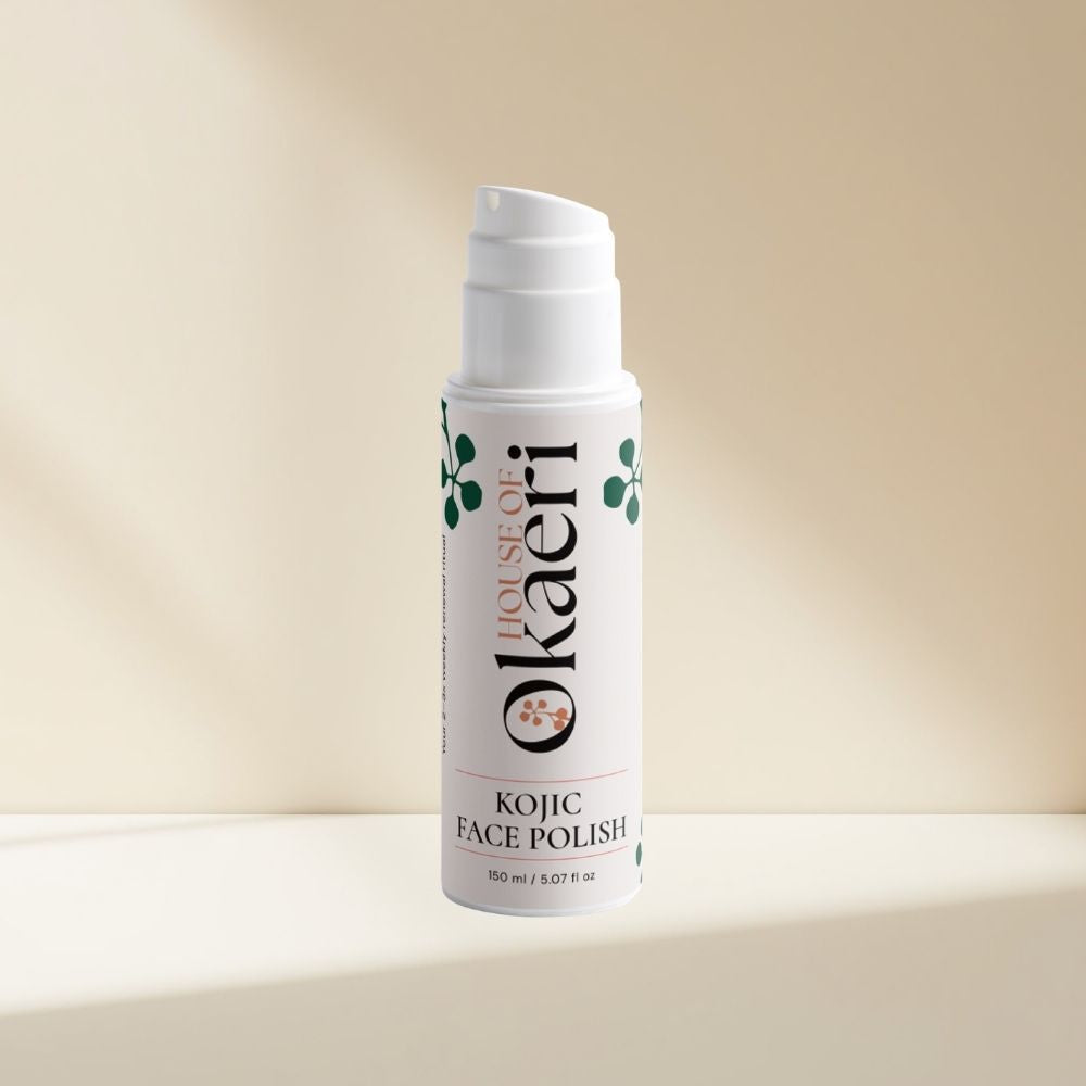 A white pump bottle of House of Okaeri Kojic Face Polish with green leaf illustrations, set against a warm beige background with soft diagonal shadows.