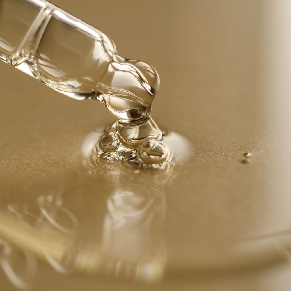 Close-up of a dropper with kojic acid liquid on a reflective surface