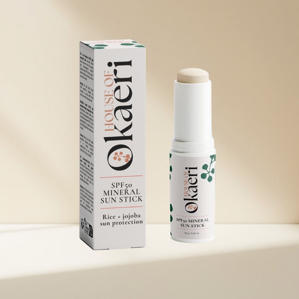 A white sunscreen stick and its matching retail box from House of Okaeri, displayed on a clean beige background with soft shadows.