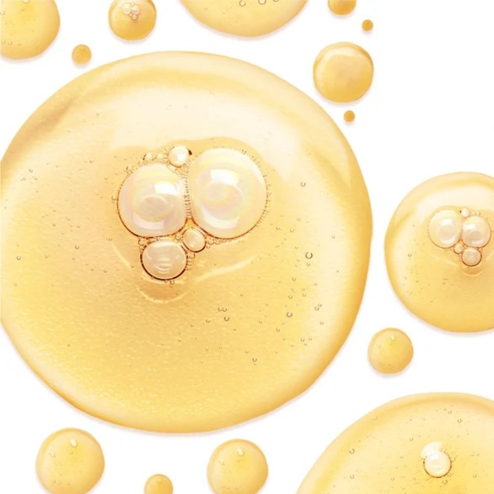 Golden-yellow cosmetic serum droplets with embedded air bubbles on a clean white background.