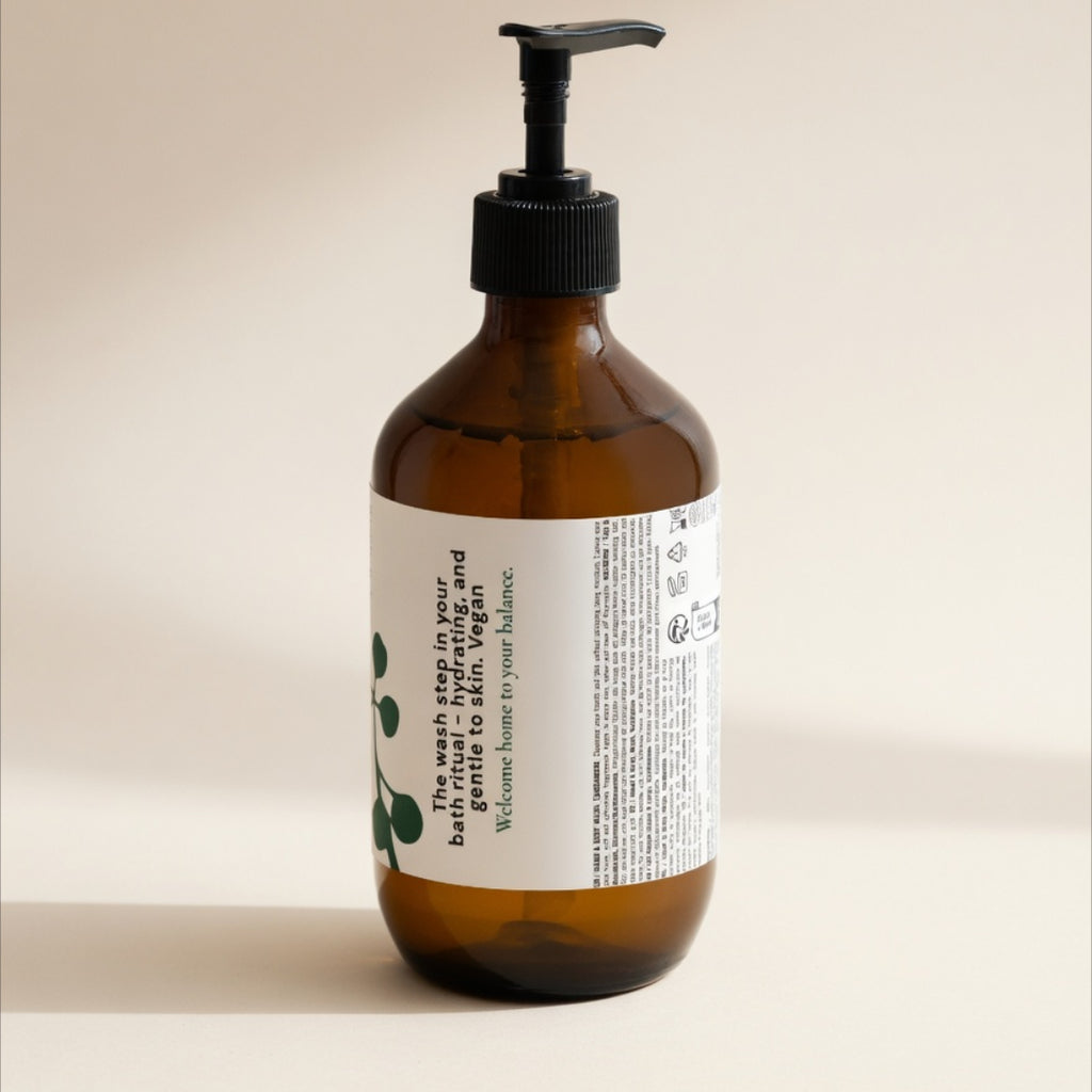 An amber glass pump bottle with a black dispenser and a white label, photographed against a plain warm beige background.