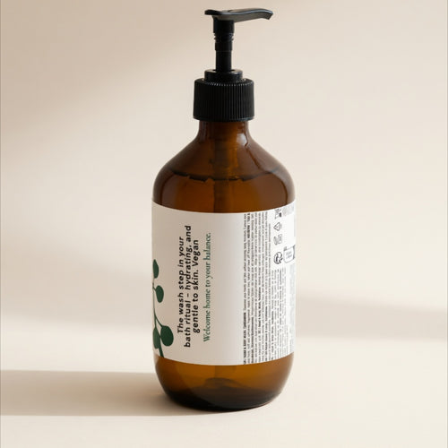 An amber glass pump bottle with a black dispenser and a white label, photographed against a plain warm beige background.